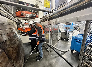 Ice Blast Works technician dry ice blasting overhead industrial machinery in a manufacturing facility
